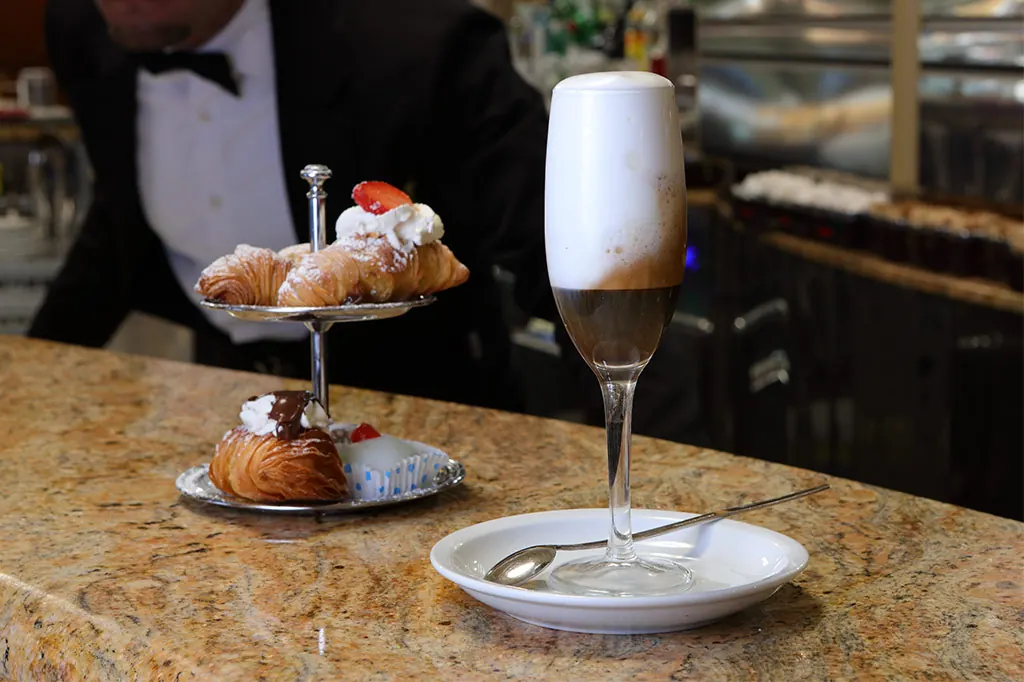 Latte macchiato e alzatina di dolci al bancone di Ceraldi Caffè